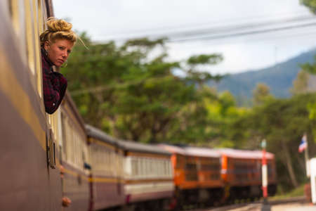Backpacker hippie girl looks through the train car window.のeditorial素材