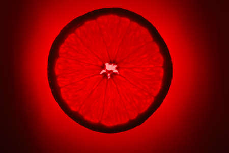 orange slice on red background, illuminatedの写真素材