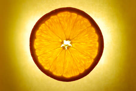 orange slice on yellow background, illuminatedの写真素材