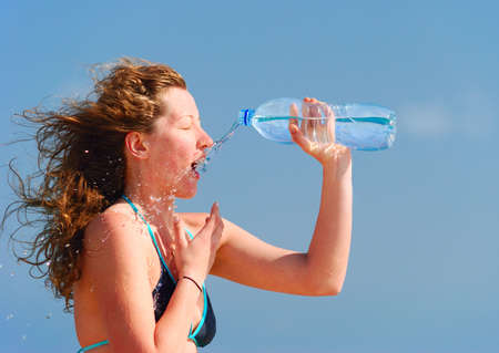 sexy woman is refreshing herself with bottle of waterの写真素材