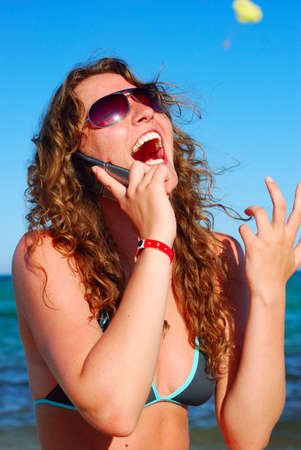 cheerful woman is talking phone near seaの写真素材