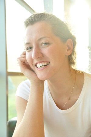 cute smiling woman sitting in cafe and looking at camera