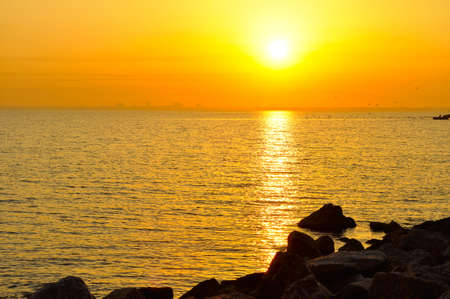 sunrise in sea with city on skylineの写真素材