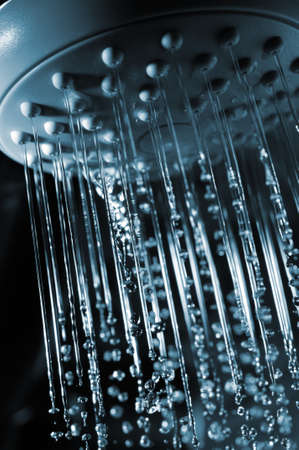 closeup view of water flowing out of shower in darkの写真素材