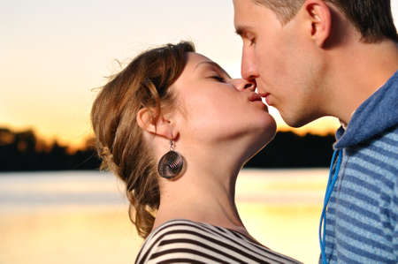 young attractive couple is kissing at sunsetの写真素材