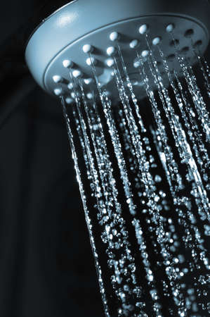 closeup view of water flowing out of shower in dark の写真素材