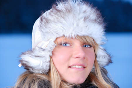beautiful young woman in furry hat at winter eveningの写真素材