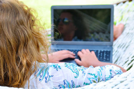 woman is lying in hammock and working on laptopの写真素材