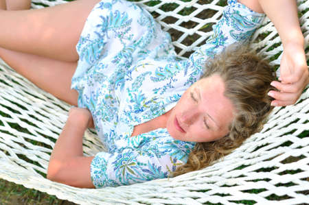 sexy woman is lying in hammock at summer in parkの写真素材