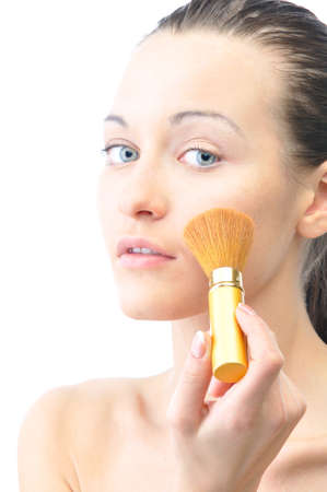 young attractive sensual woman is applying cosmetics on her face and looking at camera, isolated on whiteの写真素材