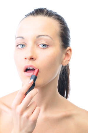 young attractive sensual woman is applying cosmetics on her face and looking at camera, isolated on whiteの写真素材