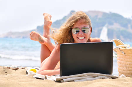 happy woman is working on laptop on beachの写真素材
