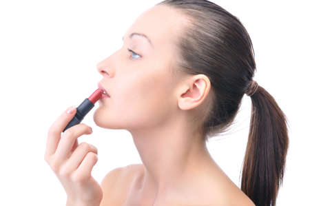 young attractive sensual woman is applying cosmetics on her face, side view, isolated on whiteの写真素材