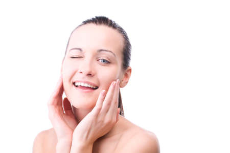 happy beautiful woman touching face and looking at camera winksの写真素材