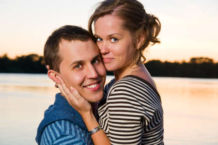 young attractive couple near lake at sunsetの写真素材