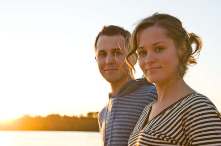 young attractive couple is walking near lake at sunsetの写真素材