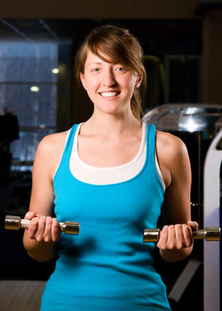 beautiful woman is exercising in gym at eveningの写真素材