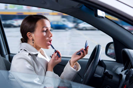elegant woman is doing makeup on the run in her car の写真素材