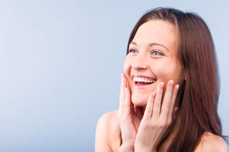 happy beautiful woman is looking sideways. Isolated on blue backgroundの写真素材