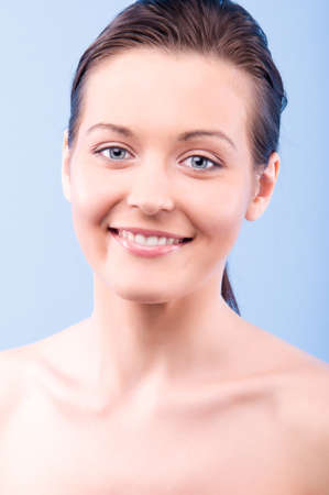portrait of a beautiful happy woman looking at camera, on blue backgroundの写真素材