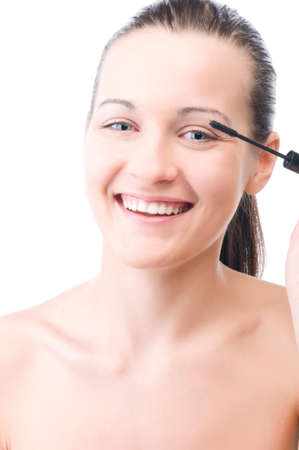 smiling woman is applying mascaraの写真素材
