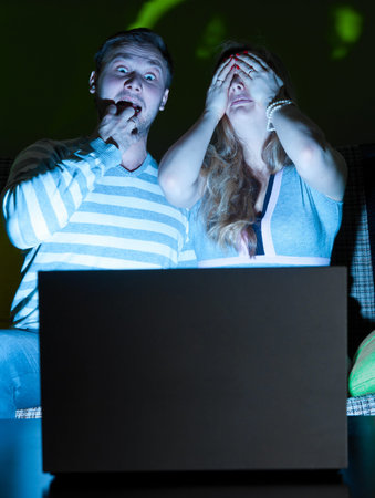 couple is watching scary movie indoors at night
