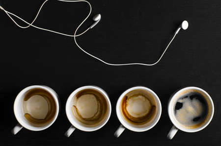 working hours  empty and full cups of fresh espresso with headphones, view from aboveの写真素材