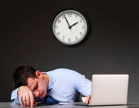 tired businessman is sleeping at his table with laptopの写真素材