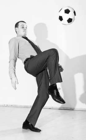 caucasian business man is playing football at office near white wallの写真素材