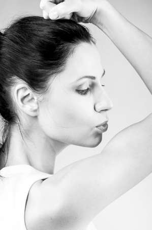 sporty woman is kissing her biceps on grey backgroundの写真素材