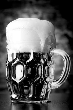 glass of lager on table against brick wallの写真素材