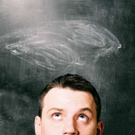 man is looking up with chalk board behind himの写真素材