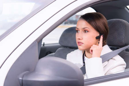 beautiful woman driver is safely talking phone in a car using a headsetの写真素材