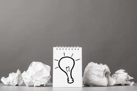 creative process  crumpled wads and notebook with bulb pictureの写真素材