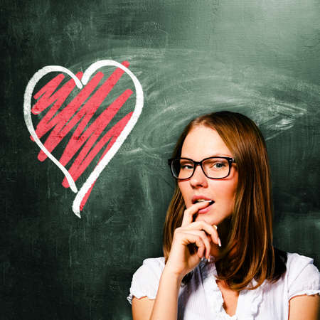 sensual student woman is standing with chalk board behind herの写真素材