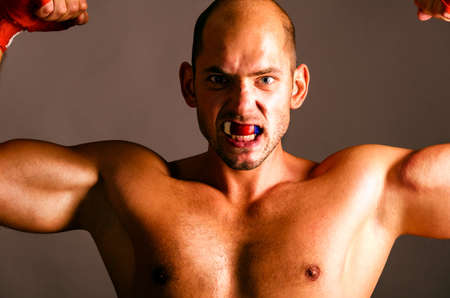 confident fighter is showing biceps on dark backgroundの写真素材