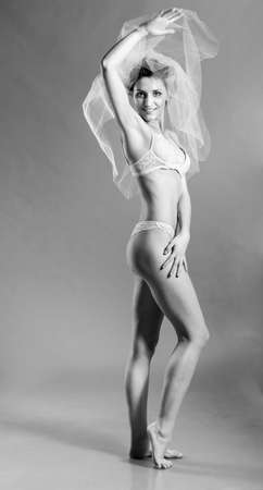 beautiful bride is standing in lingerie and wedding veil and looking at cameraの写真素材