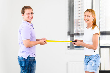 couple is measuring their new empty apartmentの写真素材