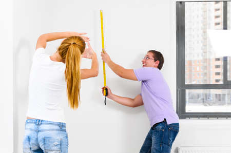 couple is measuring their new empty apartmentの写真素材