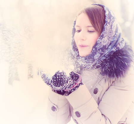 young woman is blowing snow in winter parkの写真素材