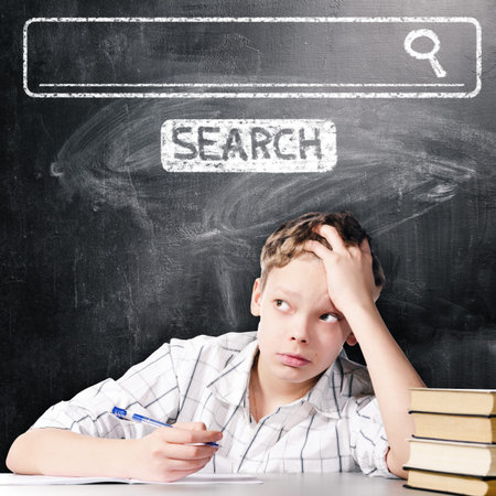 tired school boy is sitting at table with chalk board with seacrh engine behind him