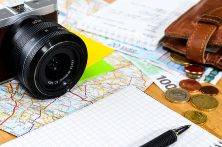 getting ready for travel, money, map and photo camera on wooden table with copy space