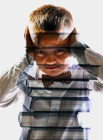 unhappy tired school boy mixed with pile of books, isolated on white backgroundの写真素材
