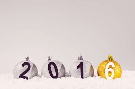 2016 year. Silver and golden decorative christmas balls on snow against grey backgroundの写真素材