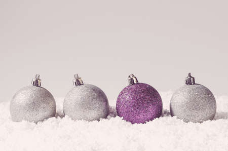 silver and purple decorative christmas balls on snow against grey backgroundの写真素材