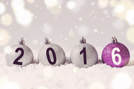 2016 year. Silver and purple decorative christmas balls on snow against grey festive background