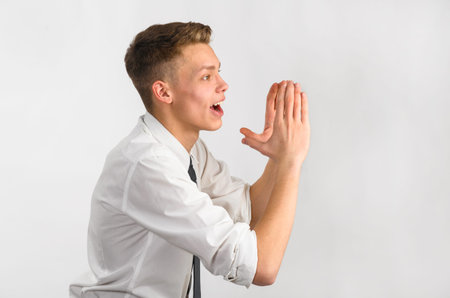 Teenager is screaming loudly with hands near his face.