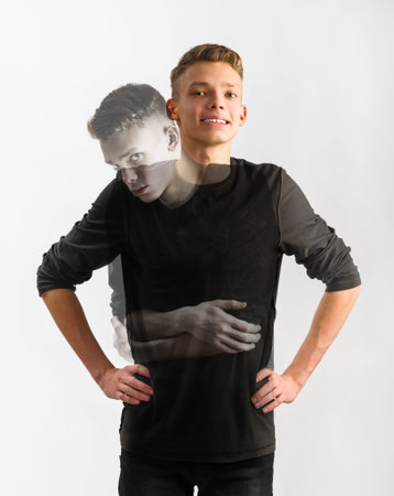 portrait of an insecure male caucasian teenager with two faces on gray backgroundの写真素材