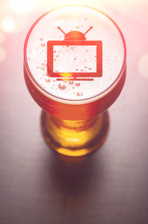 tv set symbol on foam in glass on black table, view from above