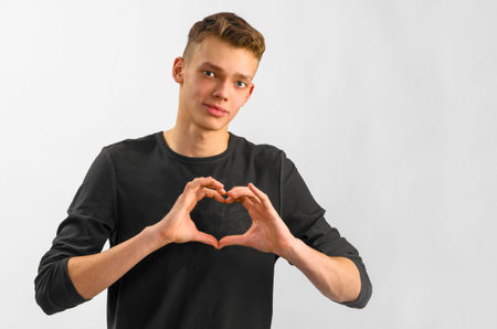 male caucasian teenager is showing his love on gray backgroundの写真素材
